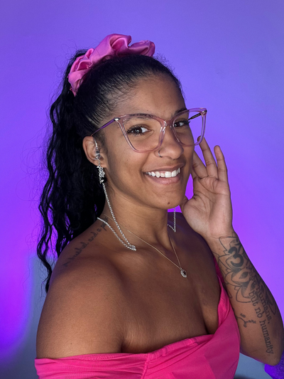 Purple Background. Black woman smiling  wearing over the ear high fidelity ear plug earrings in silver with a Black bead.
