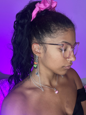 Purple Background. Black woman facing the right wearing silver high fidelity ear plug earring cuffs with clay charms of pumpkins and boiling cauldrons