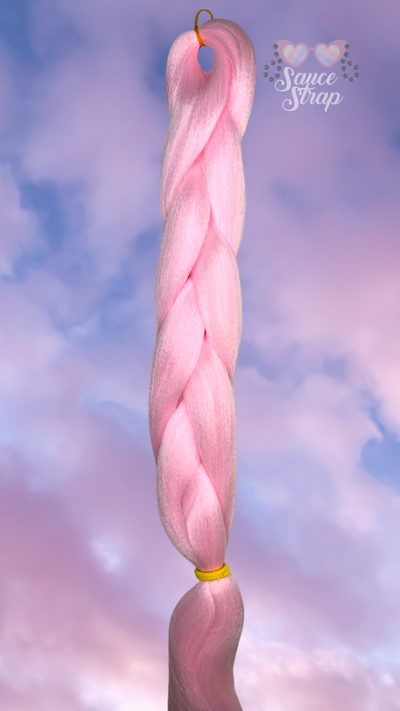 the background is of the clouds during a sunset. the sky is blue and the clouds are gradient from lilac up top down to a soft pink at the bottom of the picture. in the center is our Fairy Dust UV Reactive Braiding hair bundle. shown laying flat in a braid. it is a pastel pink.