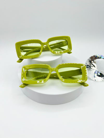 A white background with two pairs of the same sunglasses. Our PopBlocks sunglasses are rectangular shaped with thick bright and colourful frames, with lenses that match. this pair is a bright Green..